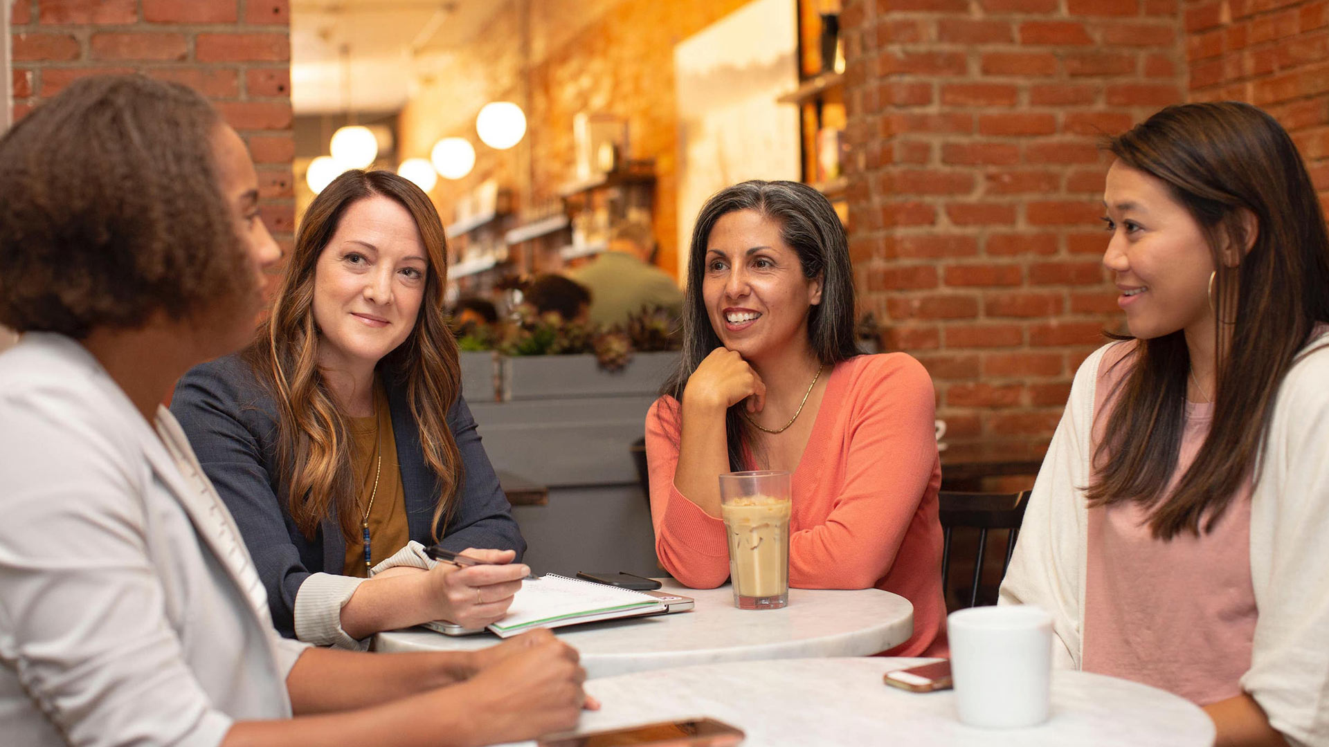 four women talking together with coffee at a restaurant