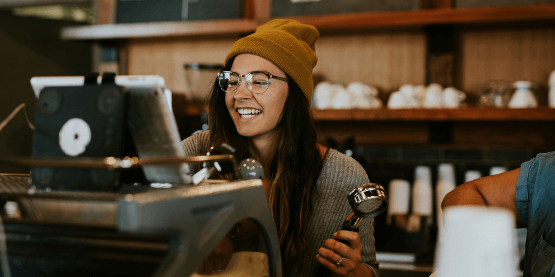 A women in a beanie smiling at a restaurant cash register.