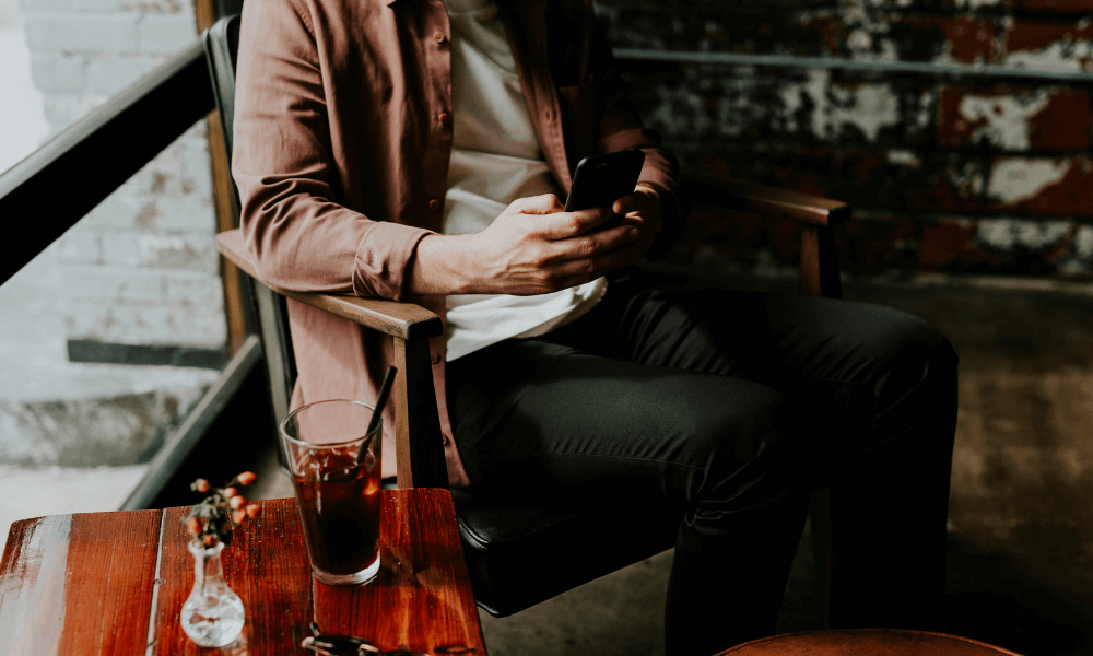 Someone sitting in a chair at a restaurant texting.