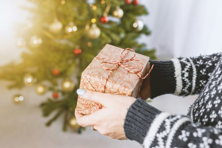 a present being held in front of a christmas tree